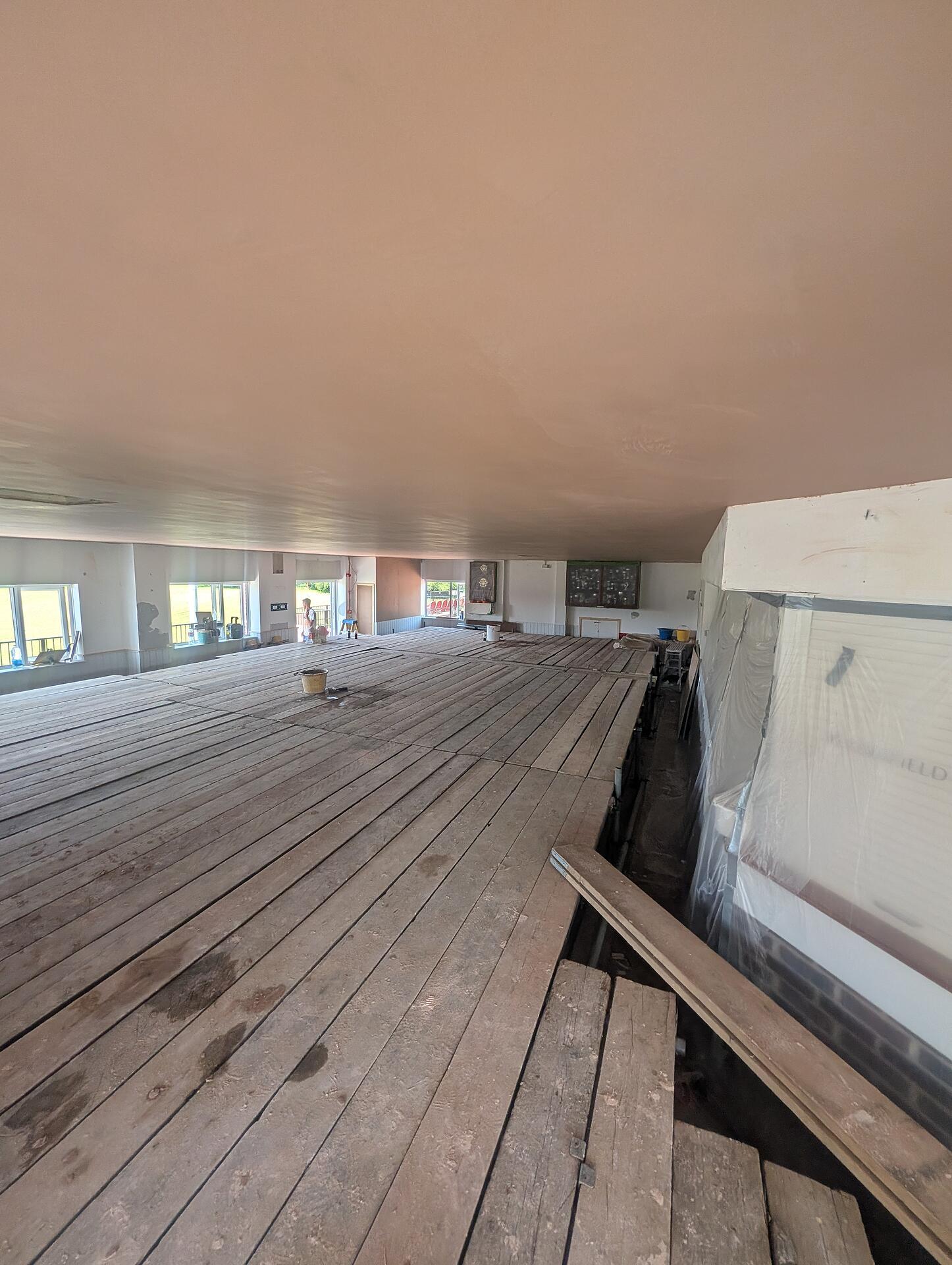 Wide view of the completed clubhouse ceiling, flat and even from end to end above the boarded floor