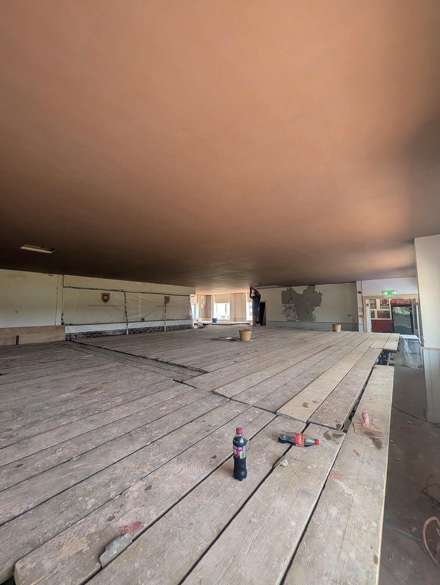 Completed clubhouse ceiling seen from the far end, the finish carried past the bar and out through the lobby
