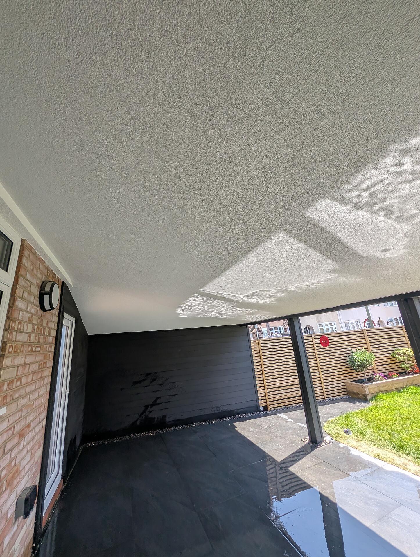Finished garden canopy with a textured render ceiling above black cladding and a newly laid slate floor