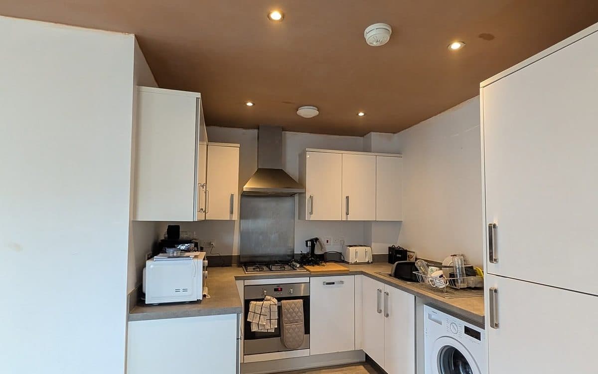 Kitchen with a freshly skimmed ceiling above white units, ready for decorating