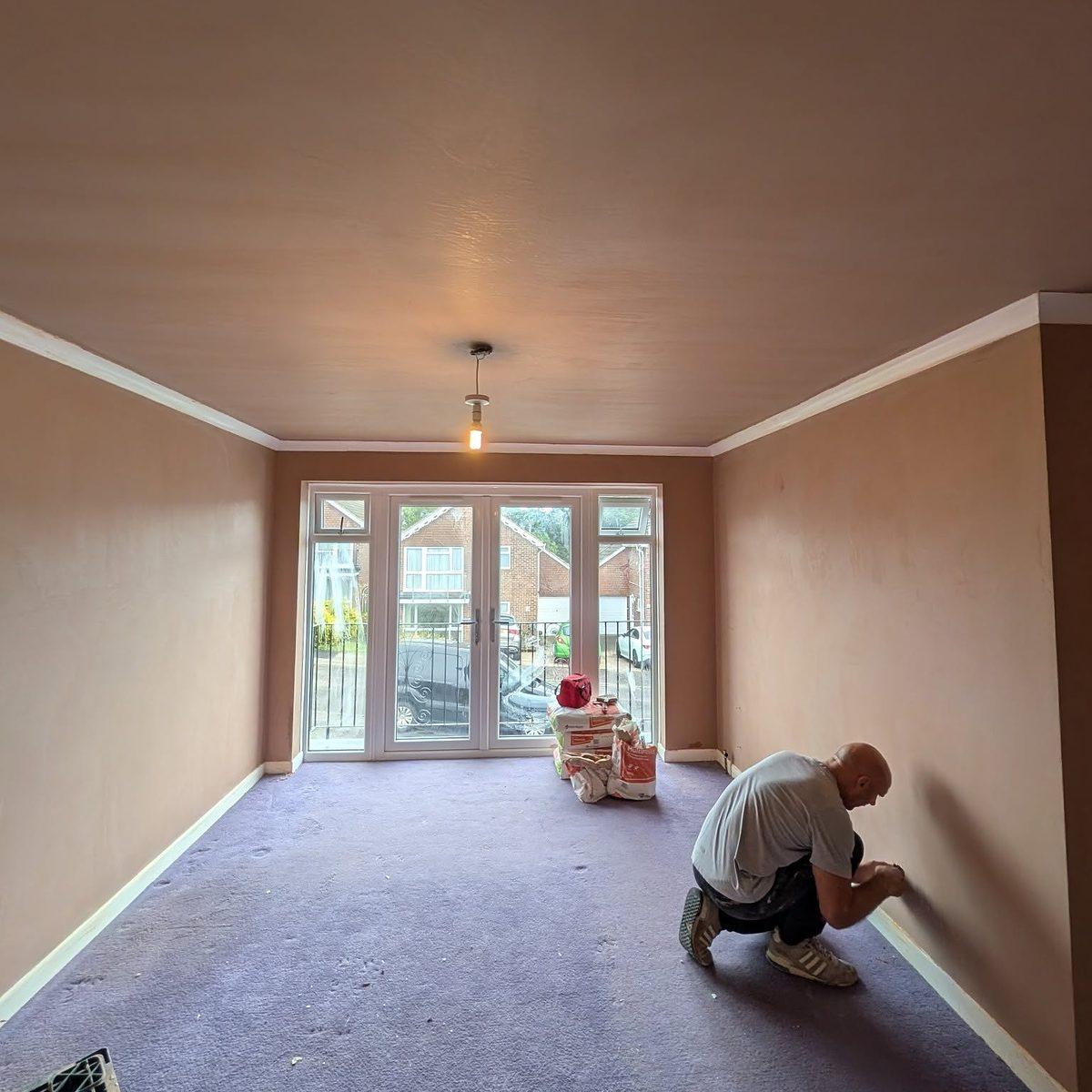 CW Plastering team member skimming a wall by hand in a room with French doors