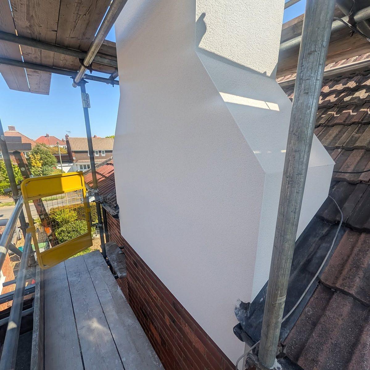 Freshly rendered gable end seen from the scaffold, a crisp finish above the original brickwork